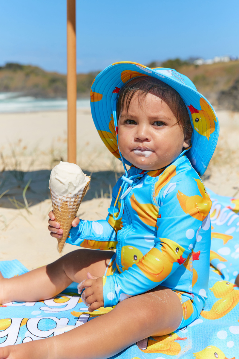 Toddler at the beach wearing the Rubber Ducks kids UPF 50+ swim hat