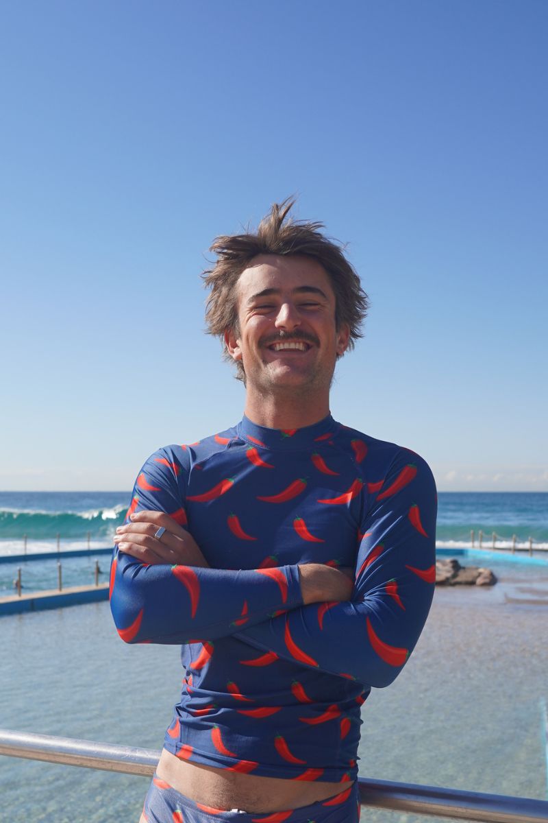 Man with arms crossed by an ocean pool in the Chilli Willies long sleeve rash vest