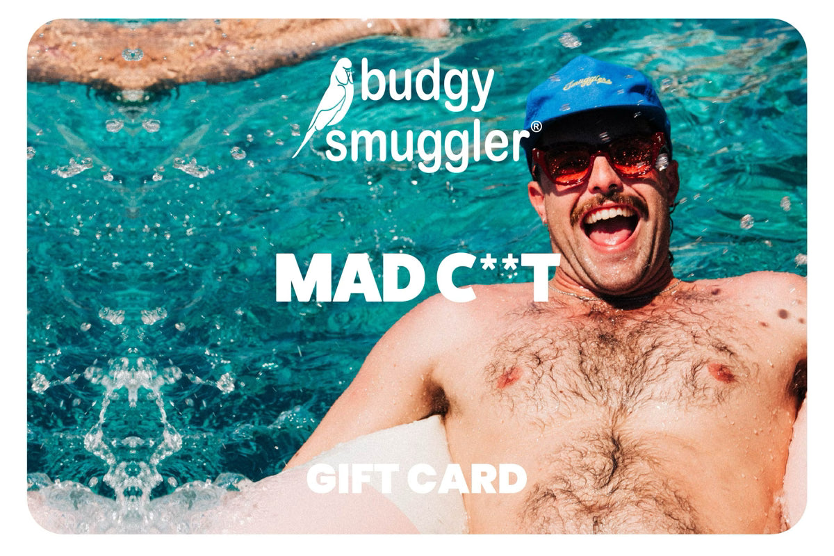 A Budgy Smuggler gift card featuring a close-up photo of a smiling man in a pool wearing a blue cap and red-tinted sunglasses. The card has a rounded rectangular shape with a subtle drop shadow, and the text 'budgy smuggler', 'MAD C**T', and 'GIFT CARD' is printed on the front.