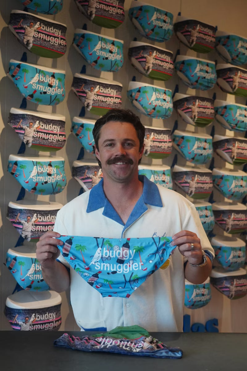 Man in a Budgy Smuggler store holding up the Travis Head Peak Performance swim briefs