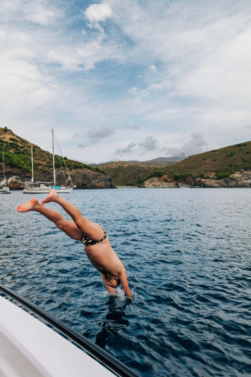 Man diving into the water with brown and cream palm tree swim briefs 