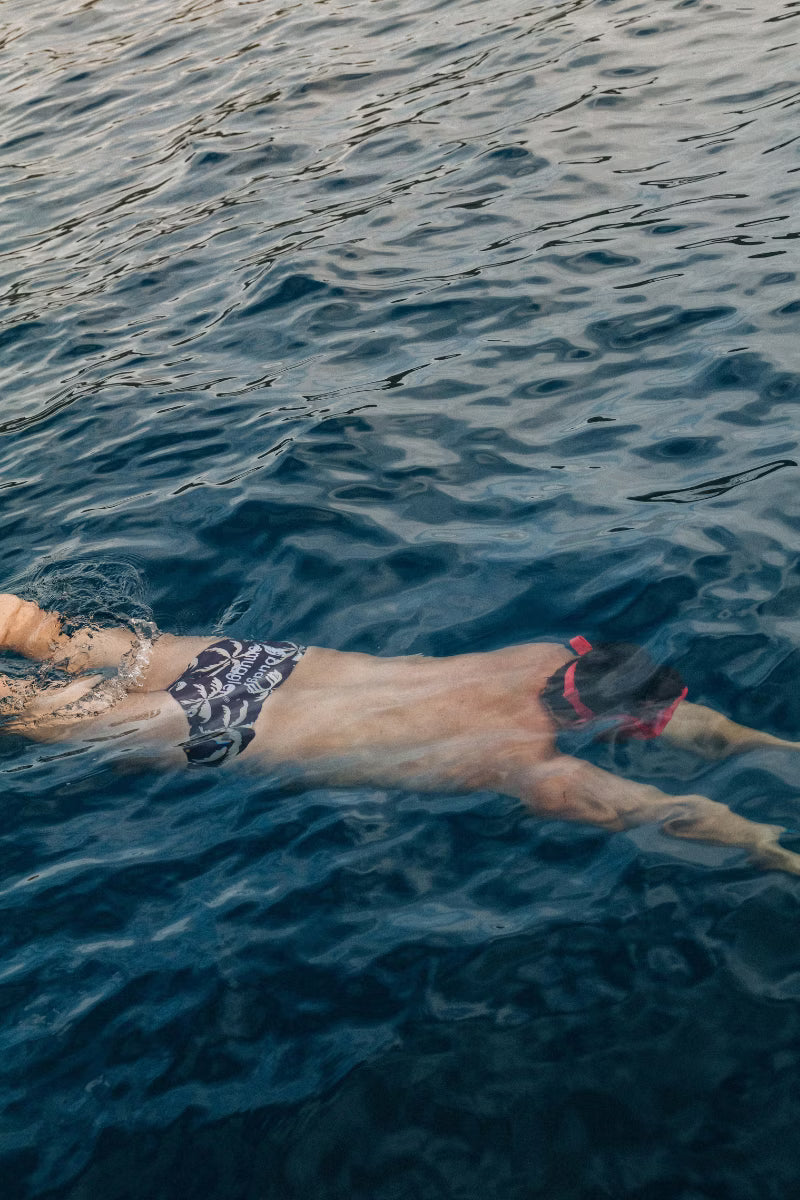 Man diving into the water with brown and cream palm tree swim briefs 
