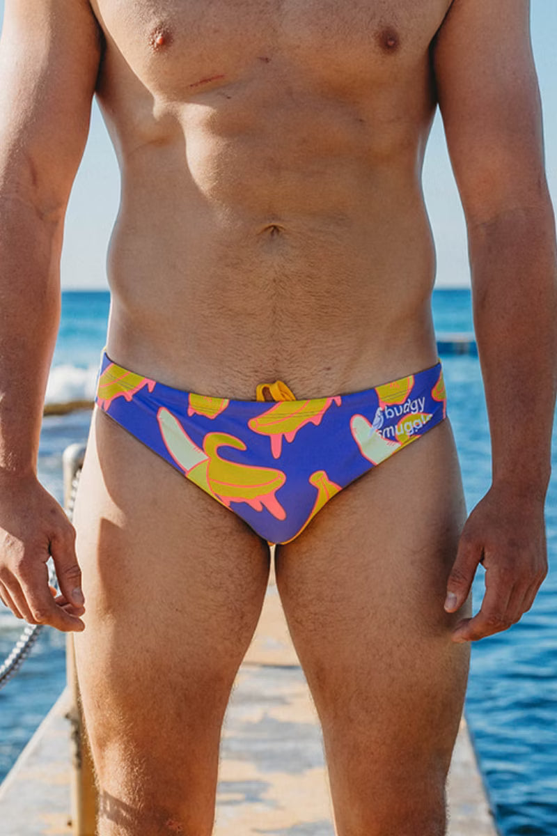 Front view of Drippy Bananas men's swimwear on an ocean pool deck