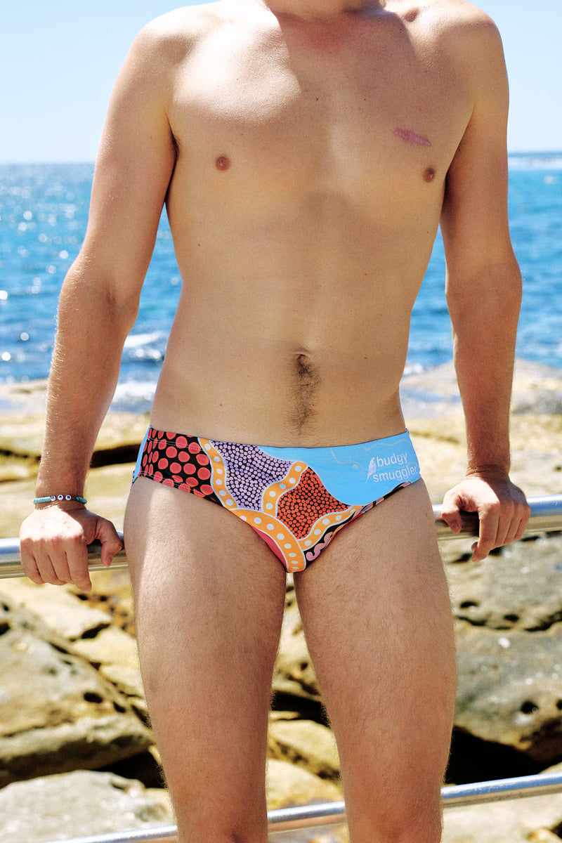 Front of the Nardurna collab swimmers on a man standing on the rocks, orange and blue dot artwork