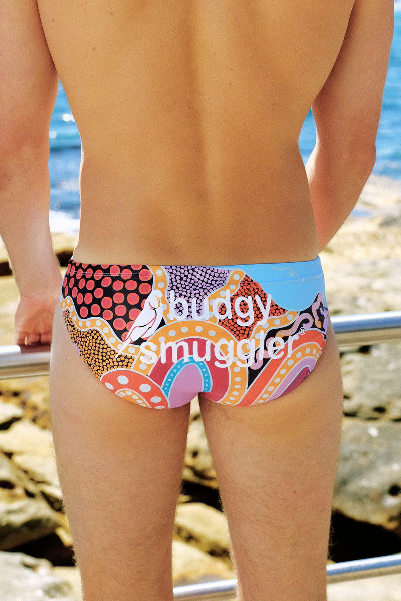 Back of the Nardurna 2.0 smugglers, red, orange and light blue Aboriginal dot artwork, by the sea