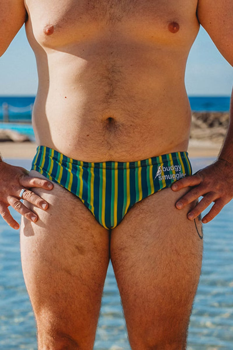 Front view of Riviera Green Stripe men's swimwear by the ocean